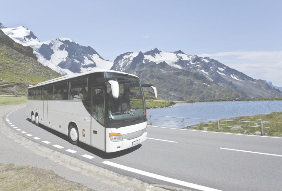 Autobus w trasie na tle jeziora i gór