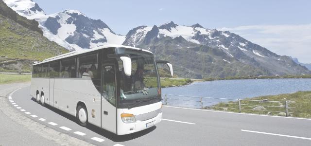Autobus w trasie na tle jeziora i gór